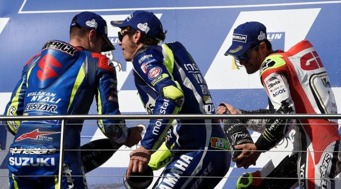 Valentino Rossi merayakan kemenangan bersama sang juara MotoGP Australia, Cal Crutchlow (kanan), dan peringkat ketiga, Maverick Vinales, di podium Sirkuit Phillip Island, Minggu (23/10/2016). (AFP/Saeed Khan)