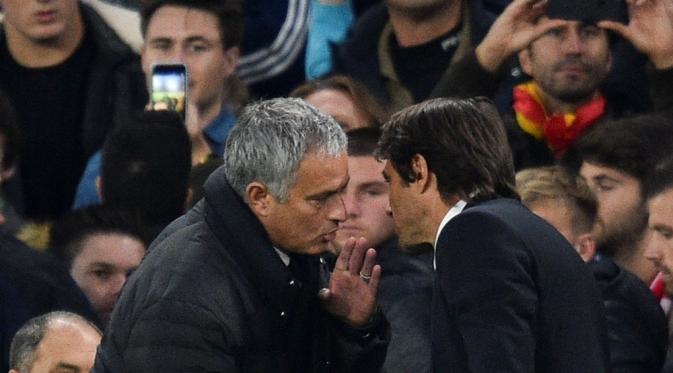 Manajer Manchester United (MU), Jose Mourinho, terlihat berbisik kepada manajer Chelsea, Antonio Conte, seusai pertandingan kedua tim, di Stamford Bridge, Minggu (23/10/2016). (AFP/Glyn Kirk). 