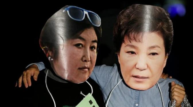 Para demonstran mengenakan topeng wajah Presiden Park Geun-hye dan temannya Choi Soon-sil (Reuters)