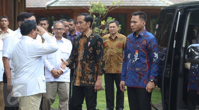Presiden Joko Widodo (Jokowi) mengulurkan tangan sementara Ketua Umum Partai Gerindra Prabowo Subianto melakukan sikap hormat saat menyambut kedatangan Presiden dan rombongan di kediamannya di Hambalang, Bogor, Senin (31/10). (Liputan6.com/Faizal Fanani)