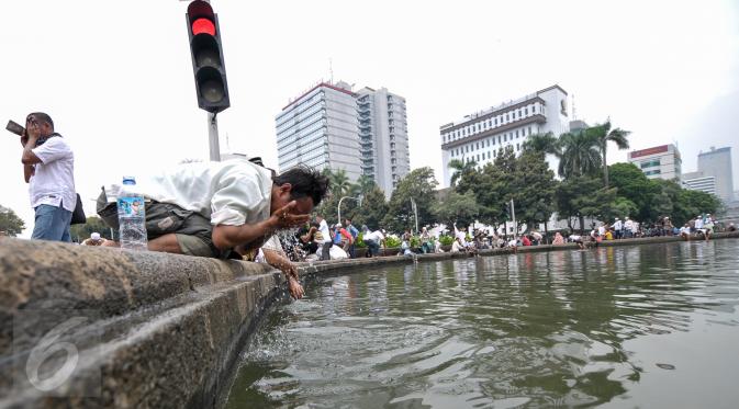 Seorang  demonstran memanfaatkan air kolam Bundaran Patung Kuda untuk wudhu salat Jumat, Jakarta, Jumat (4/11). Sebagian massa demonstan gelar salat Jumat di area Bundaran Patung Kuda. (Liputan6.com/Yoppy Renato)