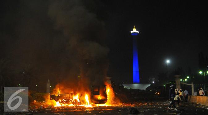 Sejumlah mobil pengangkut petugas dibakar saat Aksi Damai 4 November berujung ricuh di kawasan Monas, Jakarta, Jumat (4/11). Polisi dan Pendemo terlibat bentrok saat Massa yang diduga HMI mulai memukuli tameng polisi. (Liputan6.com/Angga Yuniar)