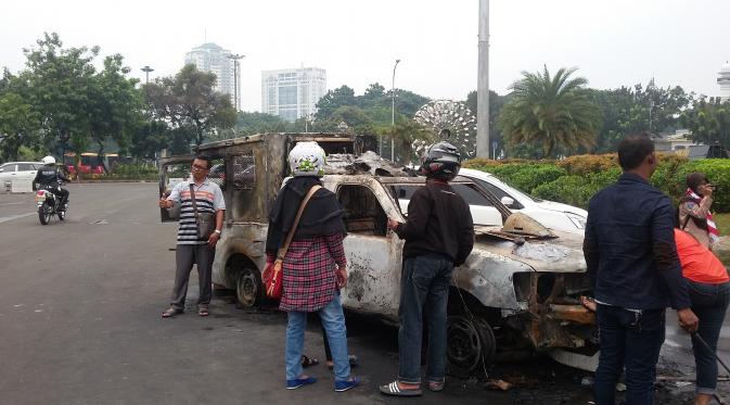 Sejumlah pengunjung Monas berfoto dengan mobil polisi yang dibakar pada demo 4 November, Sabtu (5/11/2016). (Liputan6.com/Delvira Chaerani Hutabarat)