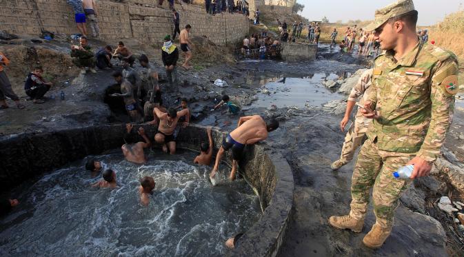 Para tentara Irak saat berada di kolam belerang di Hammam al-Ali, Mosul, Irak, (9/11). Di tengah perang melawan ISIS, mereka melepaskan penat dan lelah dengan berenang di Kolam belerang. (REUTERS/Alaa Al-Marjani)