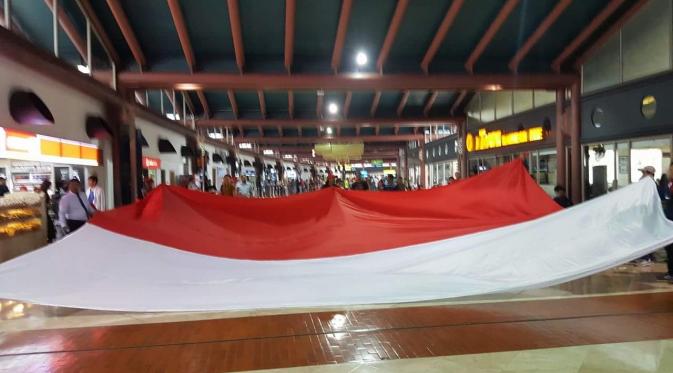Suporter Timnas Indonesia membentangkan bendera Indonesia saat berada di Bandara Internasional Soekarno-Hatta, Cengkareng, Tangerang, Jumat (18/11/20016). (Istimewa)