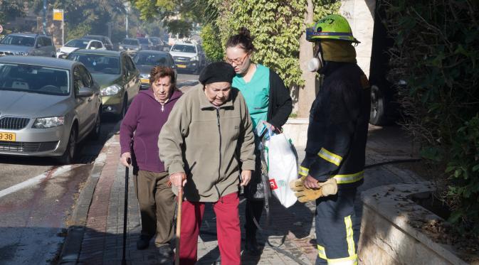 Sejumlah warga meninggalkan rumah mereka akibat kebakaran hutan hebat yang melanda kota utara Israel, Haifa, Kamis (24/11). Kebakaran terjadi setelah kekeringan selama dua bulan dan diikuti dengan angin kencang di utara kota itu. (JACK GUEZ/AFP)
