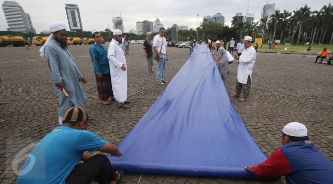 Warga mempersiapkan kelengkapan aksi damai 2 Desember di Monas, Jakarta, Kamis (1/12). Jelang aksi damai, sejumlah persiapan mulai dilakukan, seperti panggung, baris untuk Salat Jumat, hingga pengamanan dari kepolisian. (Liputan6.com/Immanuel Antonius)