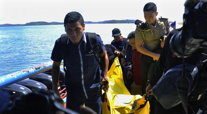 Anggota kepolisian bersiap turun dari kapal sambil mengangkat kantong jenazah berisi puing-puing dan barang-barang dari jatuhnya pesawat jenis M-28 Skytrcuk milik Polri di Pelabuhan Telaga Punggur, Batam, Kepri, Minggu (4/12). (Rezza HERDIYANTO/AFP)