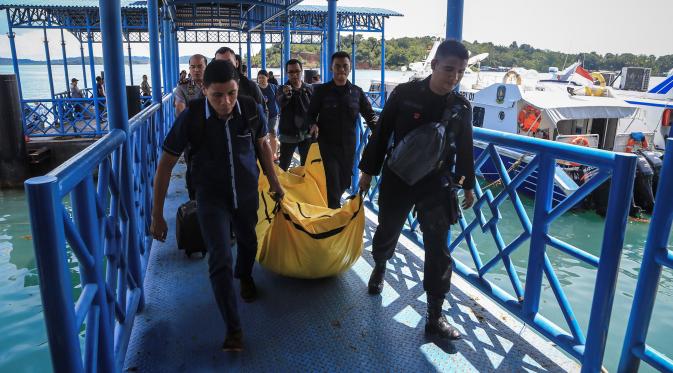 Anggota kepolisian mengangkat kantong jenazah yang berisikan puing-puing dan barang-barang dari jatuhnya pesawat jenis M-28 Skytrcuk milik Polri di Pelabuhan Telaga Punggur, Batam, Kepulauan Riau, Minggu (4/12). (Antara Foto/M N Kanwa/via REUTERS)