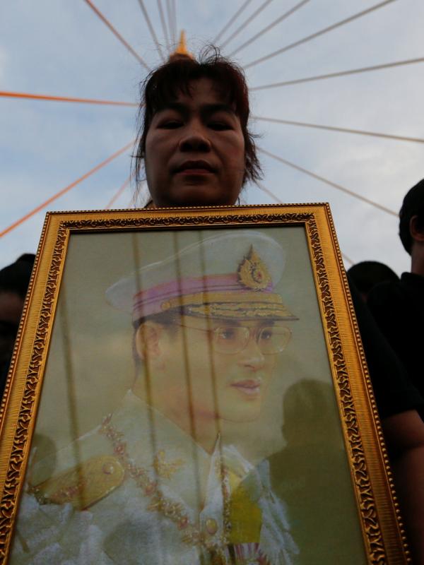 Warga membawa foto Raja Thailand, Bhumibol Adulyadej saat merayakan HUT terakhir almarhum di atas Jembatan Bhumibol, Bangkok, Thailand, Senin (5/12). Raja Bhumibol meninggal di usia 88 tahun. (REUTERS/Jorge Silva)
