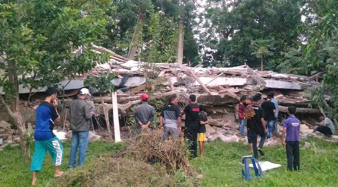 Warga berkumpul di sekitar bangunan roboh menyusul gempa 6,4 SR yang mengguncang Kabupaten Pidie Jaya, Aceh, Rabu (7/12). Empat orang dikabarkan meninggal dunia dan sekitar 30 warga mengalami luka-luka akibat tertimpa bangunan roboh. (Zian Muttaqien/AFP)