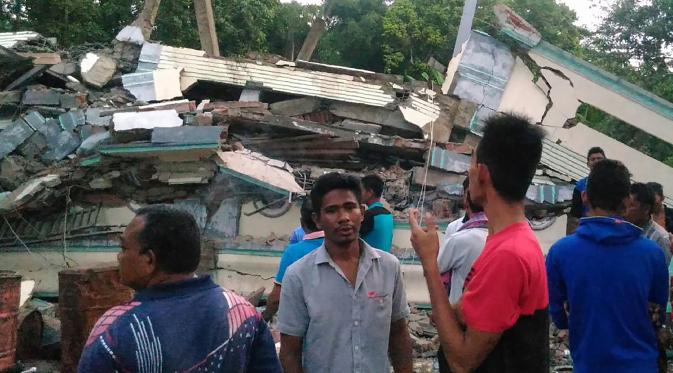 Warga mengamati sebuah bangunan yang roboh menyusul gempa 6,4 SR di Kabupaten Pidie Jaya, Aceh, Rabu (7/12). Sejumlah bangunan di Kabupaten Pidie Jaya rusak akibat gempa yang tak berpotensi tsunami tersebut. (Zian Muttaqien/AFP)