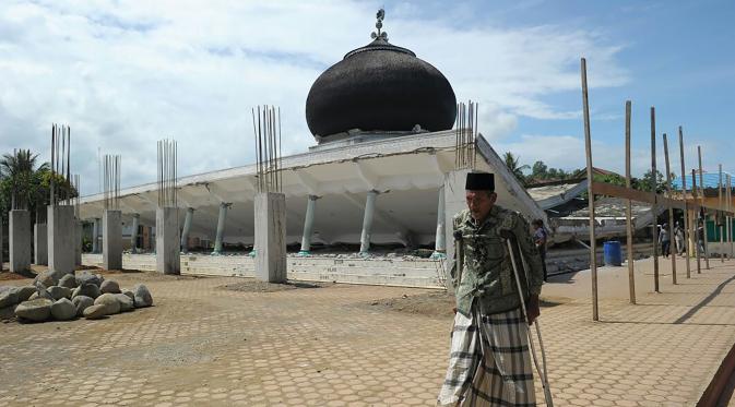 Seorang pria berjalan melewati sebuah masjid yang rusak usai gempa di Pidie Jaya, Aceh, Rabu (7/11). Selain meruntuhkan bangunan, gempa bumi berkuatan 6,4 SR ini telah menelan banyak korban jiwa. (AFP PHOTO / Chaideer Mahyuddin)