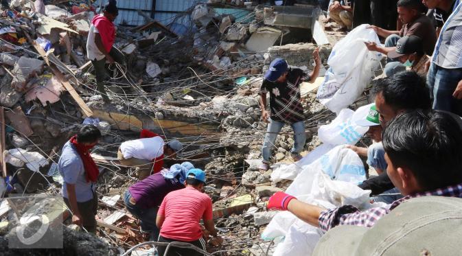 Sejumlah warga berada di sekitar Pasar Meureudu yang hancur dilanda gempa, Pidie Jaya, Aceh, Kamis (8/12). Warga yang memiliki kios di pasar tersebut beramai-ramai mencari barang yang masih dapat diselamatkan. (Liputan6.com/Angga Yuniar)