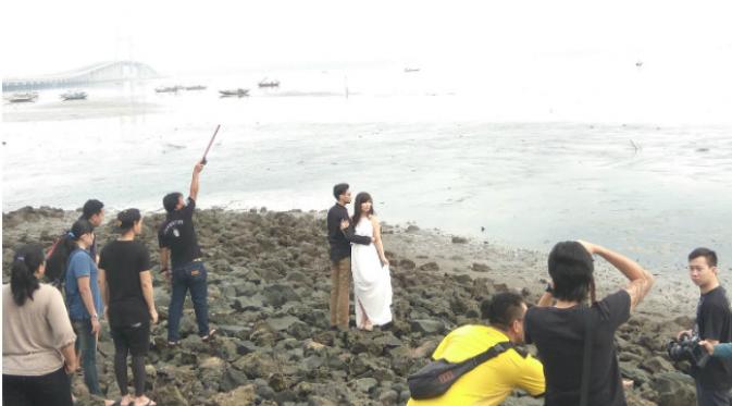 Pasangan tengah melakukan sesi foto prewedding yang mengambil latar jembatan Suramadu. (Liputan6.com/Dian Kurniawan)