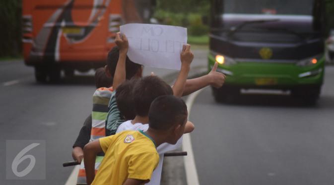 Sejumlah anak menggunakan kertas meminta bunyi klakson telolet ke bus yang lewat di jalan raya A Yani Surakarta, Solo, Kamis (22/12). Fenomena ini mendunia setelah beberapa artis dan tokoh terkenal dunia berkomentar di media sosial. (Liputan6.com/Gholib)