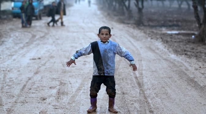 Seorang bocah laki-laki berpose di dekat kamp pengungsi Bab Al-Salam, dekat perbatasan Suriah-Turki, Provinsi Aleppo Utara, Senin (26/12). Di lokasi pengungsian ini tercatat sekitar ribuan warga yang telah lama hidup di tenda. (REUTERS/Khalil Ashawi)