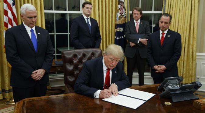 Presiden Donald Trump menandatangani perintah eksekutif pertamanya soal Obamacare (Associated Press)