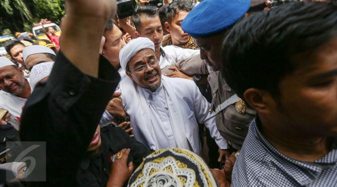 Imam Besar FPI, Habib Rizieq Shihab berusaha melewati kerumunan massa untuk memasuki gedung Dit Reskrimsus Polda Metro Jaya, Jakarta, Senin (23/1). Massa bertakbir dan melantunkan shalawat menyambut kedatangan Habib Rizieq. (Liputan6.com/Faizal Fanani)