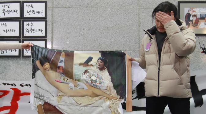 Seniman Lee Koo-Young menunjukkan lukisan Presiden Korsel, Park Geun-Hye tanpa busana yang dihancurkan di gedung Majelis Nasional, Seoul, Selasa (24/1). Lukisan itu dihancurkan kelompok konservatif dalam ajang ekshibisi lukisan parodi. (STR/YONHAP/AFP)