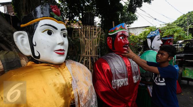 Pengrajin memperbaiki wajah ondel-ondel yang selesai dibuat di kawasan Kramat, Jakarta, Kamis (26/1). Ondel-ondel merupakan kesenian tradisional Betawi yang biasa ditampilkan dalam pesta-pesta atau hajatan. (Liputan6.com/Faizal Fanani)