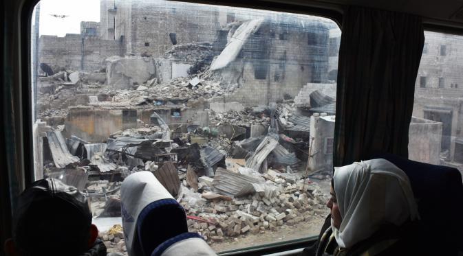 Seorang wanita melihat kota yang hancur dari balik kereta (GEORGE OURFALIAN / AFP)
