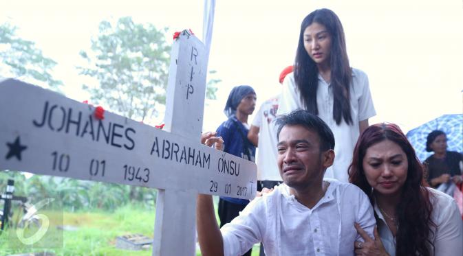 Artis Ruben Onsu menangis sambil memegang kayu nisan sang ayah, Johannes Abraham Onsu di TPU Pondok Ranggon, Jakarta Timur, Rabu (1/2). Ayah Ruben dan Jordi Onsu meninggal setelah satu minggu dirawat di sebuah rumah sakit. (Liputan6.com/Herman Zakharia)