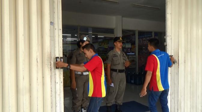 Satpol PP meminta karyawan menutup toko lantaran melanggar jam operasional (Zainul Arifin/Liputan6.com)