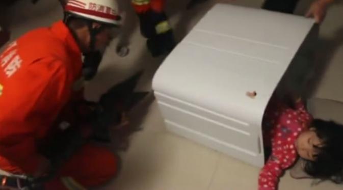 Bocah tersebut masih terjebak di dalam mesin cuci dan para petugas pemadam kebakaran berusaha keras untuk mengeluarkannya. | via shanghaiist.com