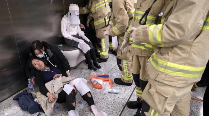 Seorang wanita korban kebakaran sedang menerima perawatan dari tim medis di Stasiun Tsim Sha Tsui, Hong Kong (10/2). Setelah polisi setempat menangkap seorang pria yang berusia 60 tahun, diduga kebakaran tersebut disengaja. (Handout / Apple Daily / AFP)