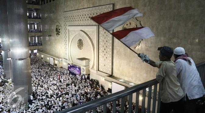 Peserta aksi mengibarkan bendera merah putih di Masjid Istiqlal, Jakarta, Sabtu (11/2). Massa yang kebanyakan mengenakan baju putih-putih ini datang dengan menggunakan kendaraan pribadi dan angkutan umum. (Liputan6.com/Herman Zakharia)
