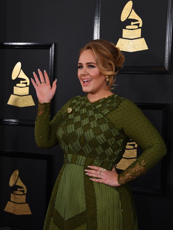 Penyanyi Inggris, Adele melambaikan tangan untuk menyapa para fans di karpet merah Grammy Awards 2017, Los Angeles, Minggu (12/2). Peraih lima nominasi Grammy 2017 itu bergaun hijau karya Riccardo Tisci dari Givenchy Haute Couture. (Mark RALSTON / AFP)