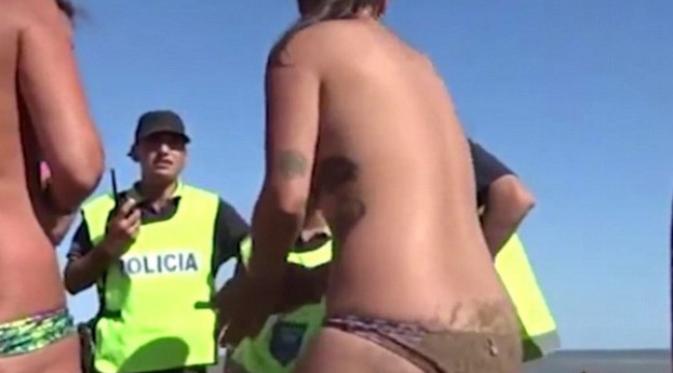Tiga perempuan topless di pantai tengah ditegor polisi untuk kembali memakai bikininya