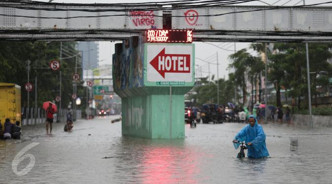 Warga mendorong sepedanya menerobos banjir yang merendam Jalan Gunung Sahari, Jakarta Pusat, Selasa (21/2). Banjir setinggi pinggang orang dewasa menyebabkan terputusnya sejumlah akses jalan untuk kendaraan bermotor (Liputan6.com/Faizal Fanani)