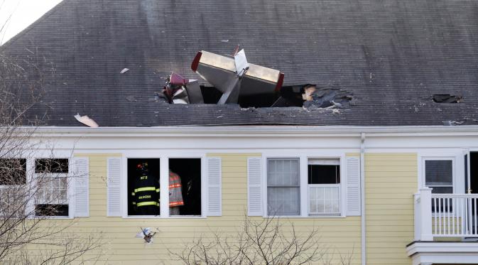 Petugas memeriksa lokasi jatuhnya pesawat ringan bermesin satu yang menabrak atap kondominium di Methuen, Massachusetts, (1/3). Penghuni rumah tidak ada yang cidera. (AP/Elise Amendola)