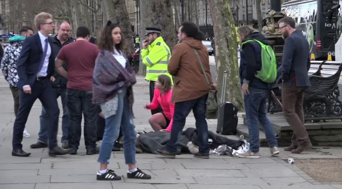 Seorang wanita tergeletak setelah menjadi korban serangan teror di dekat gedung Parlemen Inggris, London, Rabu (22/3). Pelaku ditembak mati oleh anggota polisi lainnya yang berada di gedung parlemen setelah sempat menikam seorang anggota polisi (AP Photo)