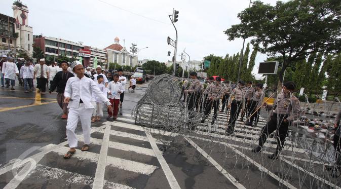 Massa aksi 31 Maret melintasi petugas polisi yang sedang memasang kawat berduri di sekitar Istana Negara, Jakarta, Jumat (31/3). Kawat berduri tersebut dipasang untuk mengantisipasi ricuh aksi 31 Maret. (Liputan6.com/Immanuel Antonius)