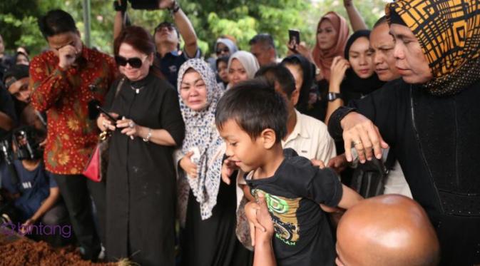 Anak Renita Sukardi menyaksikan jenazah ibunya masuk ke liang lahat. (Nurwahyunan/Bintang.com)