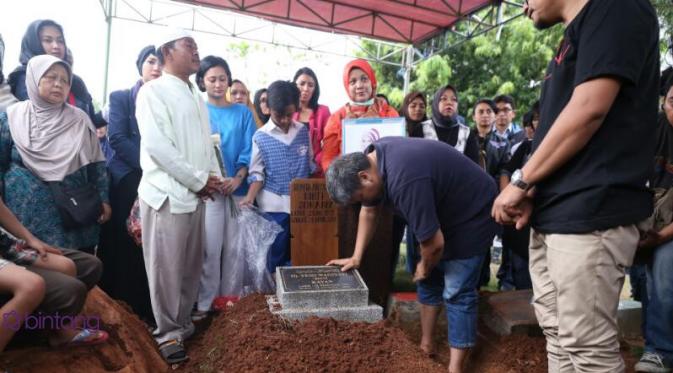 Suami Renita Sukardi memegang nisan istri tercinta. (Nurwahyunan/Bintang.com)