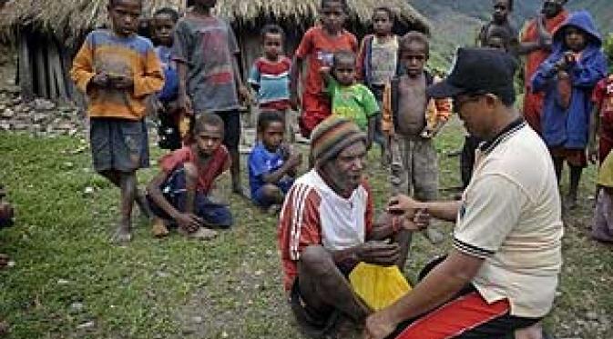 Petugas Puskesmas Illu Saparuddin (kanan) memberikan layanan kesehatan kepada warga yang tinggal di pedalaman kampung Nioga, Distrik Illu, Puncak Jaya, Papua.(Antara)