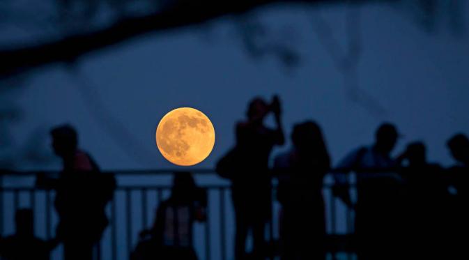  Orang-orang berdiri di sebuah jembatan di Manhattan, New York untuk melihat bulan purnama (REUTERS / Carlo Allegri)
