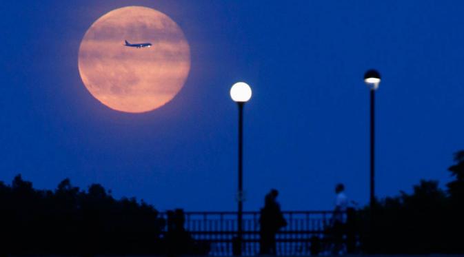 Pesawat tampak membelah sinar bulan purnama di Ottawa, Kanada   (REUTERS/Blair Gable)