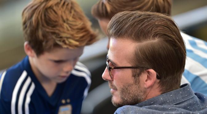 Selama pertandingan di stadion Maracana, Brasil, David Beckham terlihat berbincang dengan anaknya, Cruz Beckham, Senin (14/7/14). (AFP PHOTO/Nelson Almeida)