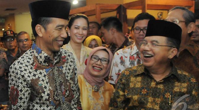 Jokowi dan JK tersenyum satu sama lain setelah memakai kopiah, Pasaraya Blok M, Jakarta, Kamis (2/10/2014) (Liputan6.com/Herman Zakharia)