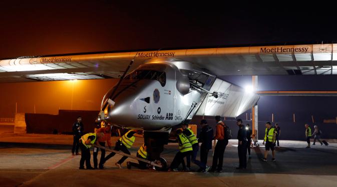 Sejumlah teknisi saat mendorong pesawat Solar Impulse 2 di bandara Ahmedabad, India, Rabu (11/3/2015). Pesawat buatan Swiss tersebut mendarat setelah menempuh perjalanan selama 15 jam.  (Reuters/Amit Dave)