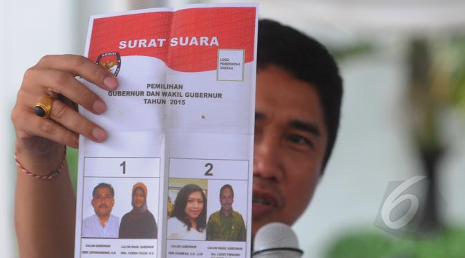 Seorang pegawai KPU memperlihatkan surat suara yang tidak sah saat simulasi di Halaman Gedung KPU RI, Jakarta Pusat, Selasa (7/4/2015). Surat suara dinyatatakan tidak sah karena dicoblos di luar kotak.   (Liputan6.com/Herman Zakharia)