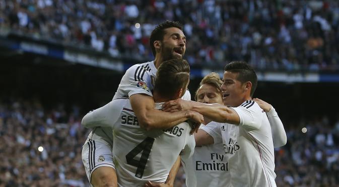 Sergio Ramos dipeluk oleh rekan-rekan setimnya usai mencetak gol pertama Madrid ke gawang Malaga. (AP Photo/Andres Kudacki)