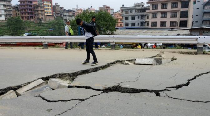 Sejumlah warga Kathmandu melihat jalan yang rusak akibat gempa , Minggu (26/4/2015). Gempa berkekuatan 7,8 Skala Richter dikabarkan telah menelan korban sekitar 2000 jiwa. (AFP Photo/Prakash Mathema)