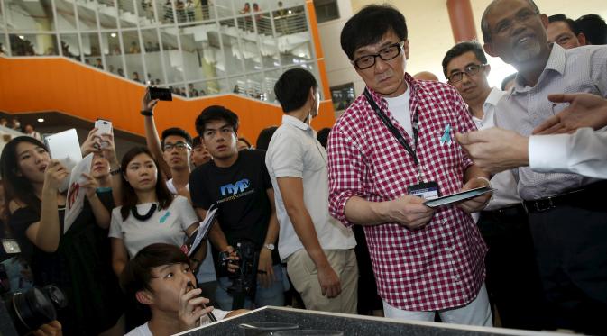 Jackie Chan menyempatkan diri untuk melihat sebuah pameran saat peluncuran aplikasi mobile game anti-narkoba 'Aversion', Singapura, Kamis (7/5/2015). Aplikasi ini sebagai kepedulian tentang bahaya penyalahgunaan narkoba. (Reuters/Edgar Su)