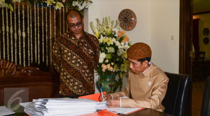 Presiden Jokowi (kanan) didampingi Sekretaris Kabinet Andi Widjajanto (kiri) ketika menandatangani sejumlah berkas saat berkantor di rumahnya di Jalan Kutai Utara RT.08/RW.07 Sumber, Solo, Jateng, Rabu (10/6/2015). (Liputan6.com/Faizal Fanani)